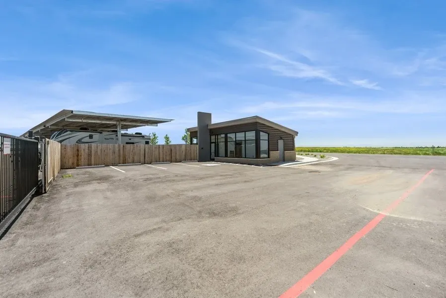 Parking spaces in front of the security office for a RV parking lot. A RV can be just beyond the fence.
