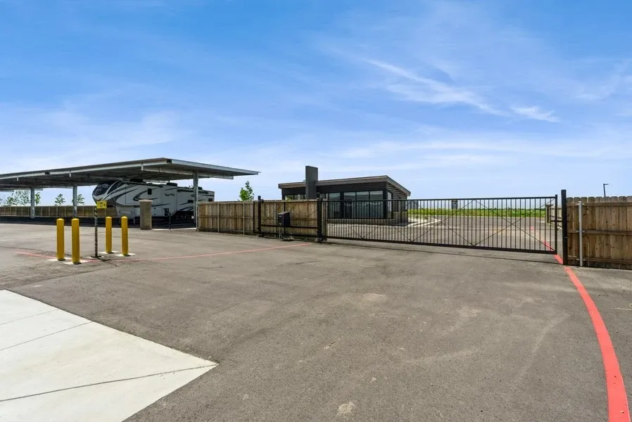 Parking spaces in front of the security office and entry gate for a RV parking lot. A RV can be just beyond the fence.