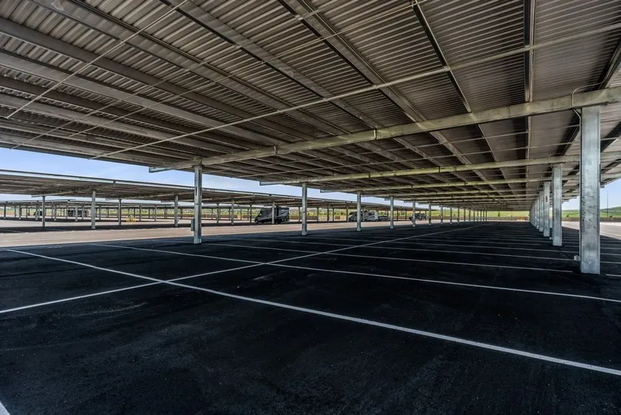 Empty lot of covered parking spaces with a few RVs parked in the distance