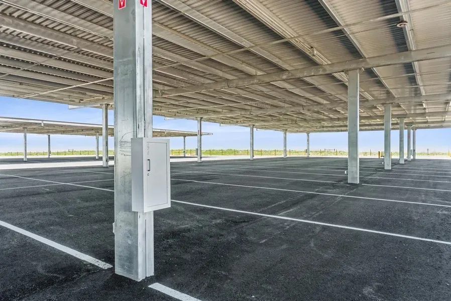 A close up shot of empty covered parking spaces. A white utility box can be seen.