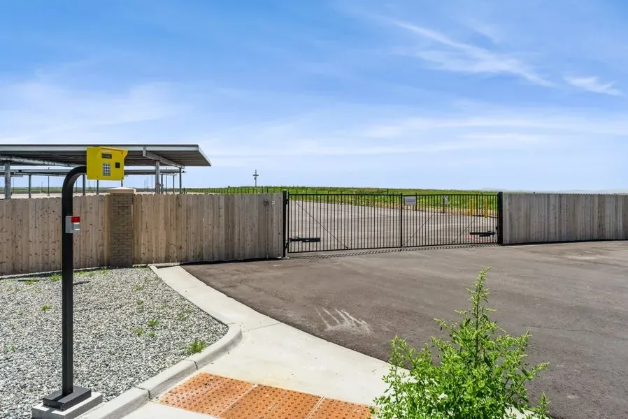 A wooden fence and access gate with a yellow security panel in the foreground.
