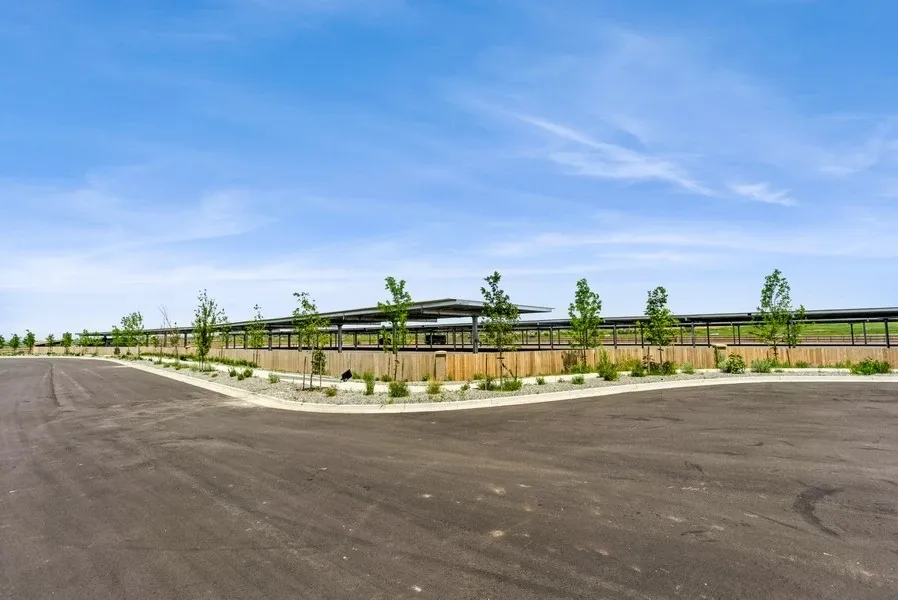 A wooden security fence protects a lot of covered parking spaces.