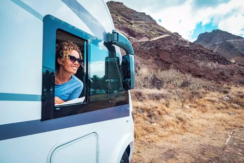 Woman smiling out of RV window.