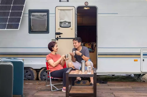 A couple sitting and relaxing outside of their RV.